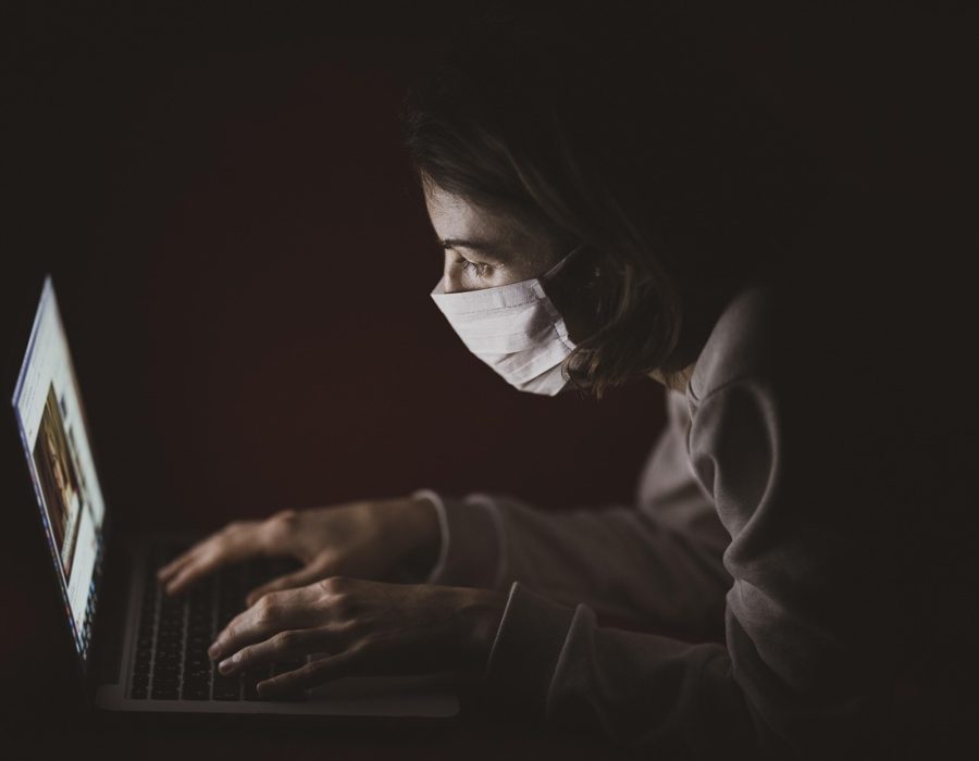 一位教师在复古风格的机房里俯身查看学生电脑屏幕，木质桌面上摆着老式键盘与笔记，暖橙色灯光从侧面打来，画面呈现胶片颗粒质感的怀旧教学场景